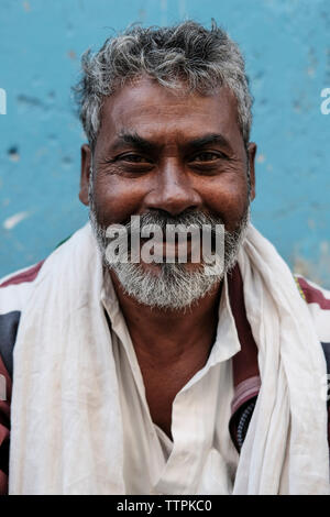 Portrait of smiling bearded mature man with white scarf against wall in town Stock Photo