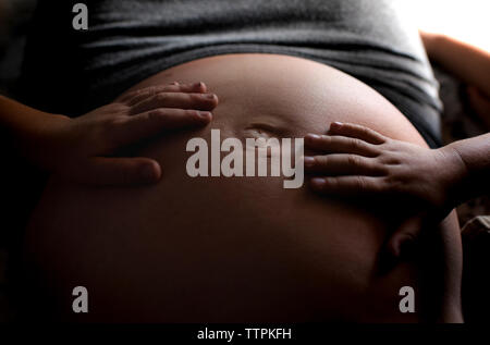 Cropped image of siblings touching pregnant mother stomach Stock Photo