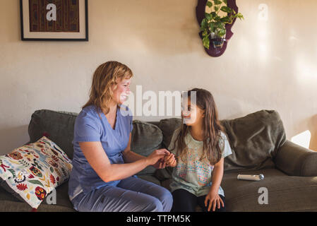 High angle view of doctor checking pulse of girl while sitting on sofa at home Stock Photo
