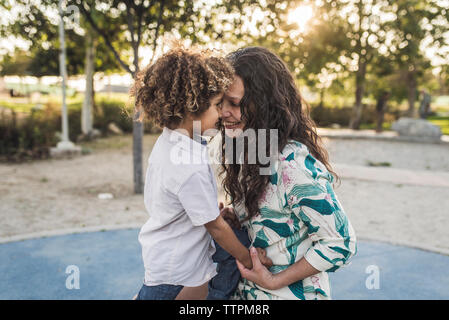 Smiling mother playing with son at park Stock Photo