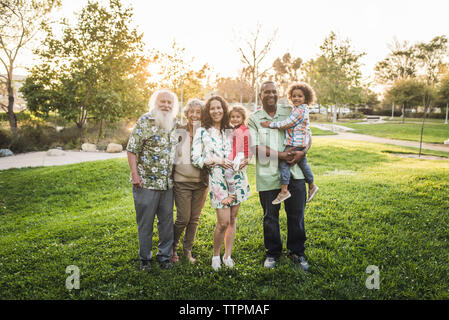 Portrait of happy multi-generation family standing on grassy field at park Stock Photo