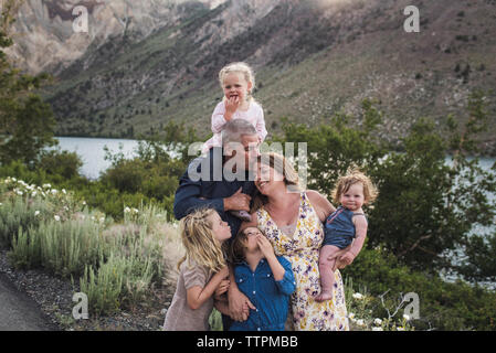 Romantic parents with cute daughters standing against mountain in forest Stock Photo