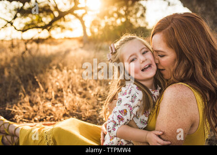 Close up of laughing young girl embraced by mother in California field Stock Photo