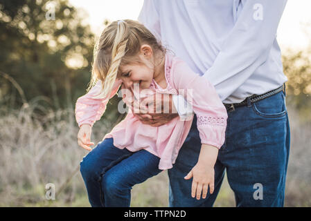 Granddaughter being swung by grandfather, playing in field Stock Photo