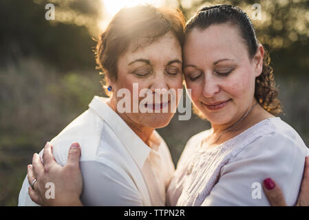 Close up of adult mother and daughter embracing and closing eyes