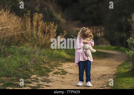 Little girl walking with her stuffed animal and hugging it Stock Photo