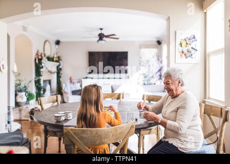 Multigenerational family playing with tea set at kitchen table Stock Photo