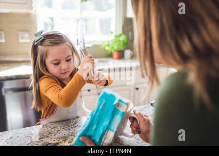 Grandmother and granddaughter making breakfast pancakes in the kitchen Stock Photo