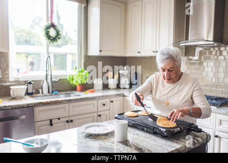 Senior woman making pancakes for her family Stock Photo