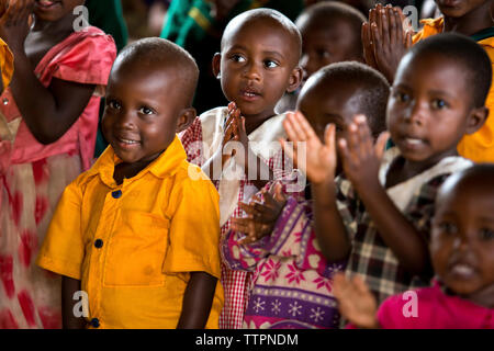 Children clapping hands in classroom Stock Photo