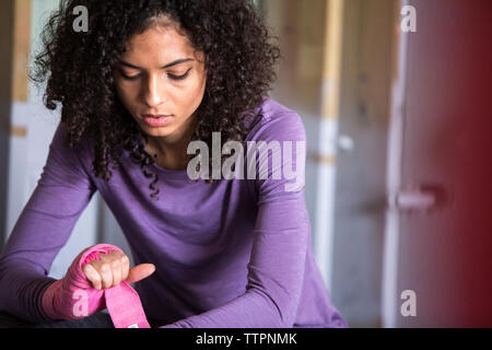 Female boxer wrapping wristband on hand in gym Stock Photo