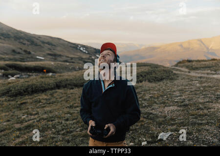 Man looking up while operating drone's remote control against mountains Stock Photo