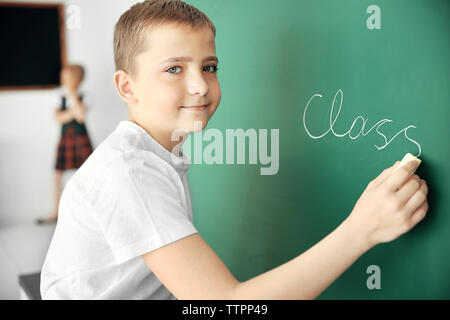 Cute schoolboy writing on chalkboard Stock Photo