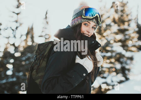 Portrait of confident young woman with backpack wearing ski goggles during winter Stock Photo