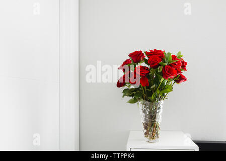 Close-up of roses in vase on table by wall at home Stock Photo