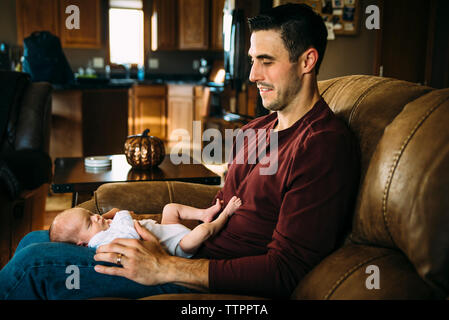 Cute sleeping daughter lying on father's laps at home Stock Photo