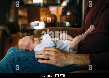 Cute daughter lying on father's laps at home Stock Photo