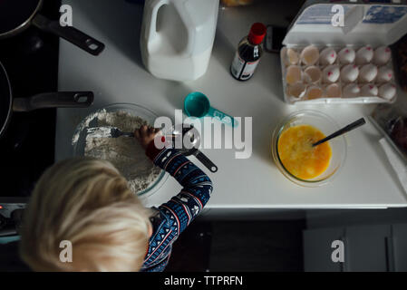 High angle view of baby boy mixing flour in bowl at kitchen Stock Photo