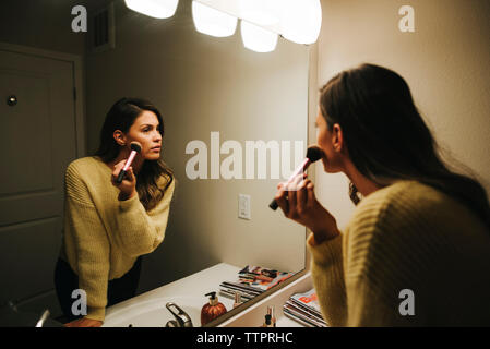 Woman applying make-up reflecting on mirror Stock Photo