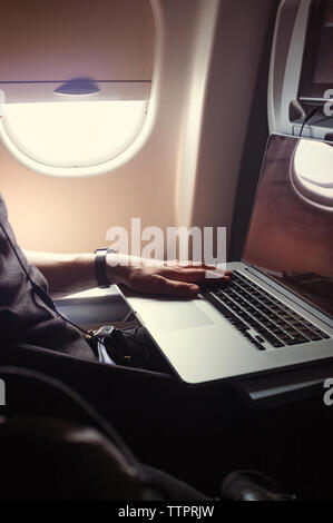 Cropped image of man using laptop while travelling in airplane Stock Photo