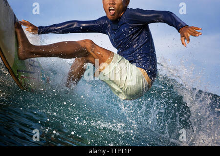 Excited young man surfing on sea Stock Photo