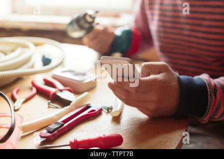 Midsection of man using smart phone at workshop Stock Photo