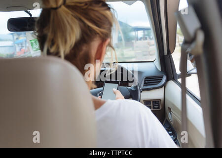 Rear view of man using mobile phone while sitting in car Stock Photo