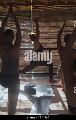 Instructor teaching Warrior 1 pose to women in studio Stock Photo