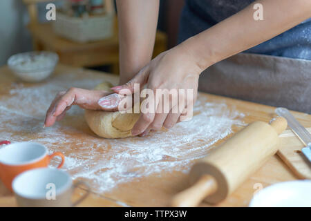 Midsection of woman kneading dough on table at home Stock Photo