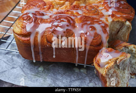 Iced cinnamon buns on cooling rack over wax paper at kitchen Stock Photo