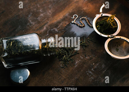 Close-up of tea strainer with dried leaves in jar on wooden table Stock Photo