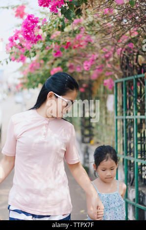 Mother holding daughter's hands while walking at park Stock Photo