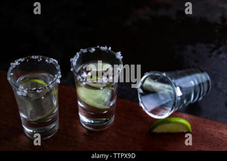 High angle view of tequila with lime slices on wooden table Stock Photo