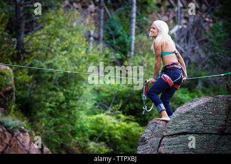 Side view of woman holding rope while standing on rock Stock Photo