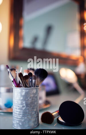 Makeup brushes in container on vanity table Stock Photo