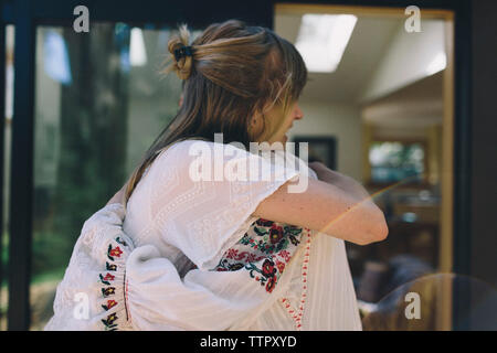 A warm embrace between bride and bridesmaid as they hug and smile. Stock Photo