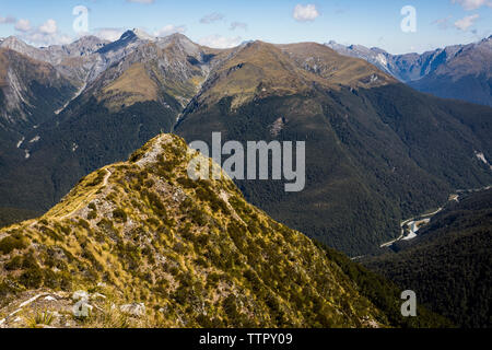 Figure on ridge trail overlooking mountains and valley in New Zealan Stock Photo