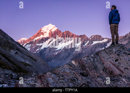 Figure on a rock looking towards Mount Cook at dusk in New Zealand Stock Photo
