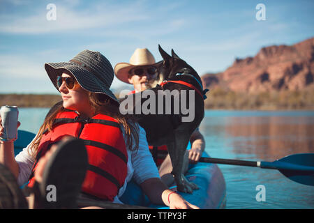 Friends with dog sitting in inflatable kayak on lake Stock Photo