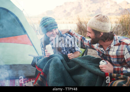 Happy couple holding beer cans enjoying at camp site Stock Photo