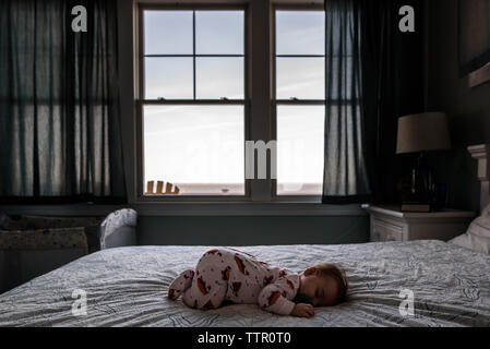 infant sleeping on bed with view of the ocean outside the window Stock Photo