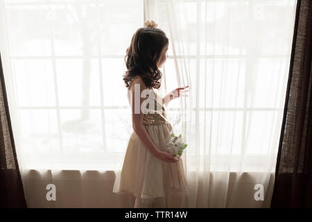 Side view of girl standing by window at home Stock Photo