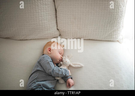 High angle view of cute baby boy sleeping with stuffed toy on bed Stock Photo