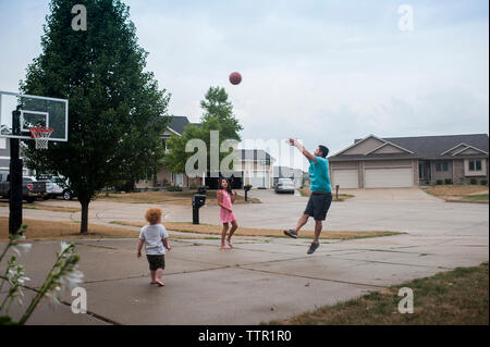 Father playing basketball with children on court Stock Photo