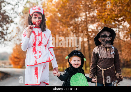 Kids stand together in halloween costumes before trick or treat Stock Photo