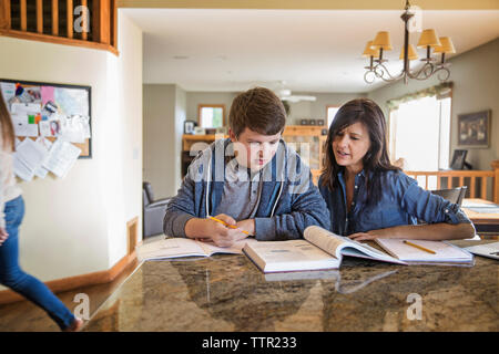 Mother teaching son on table at home Stock Photo