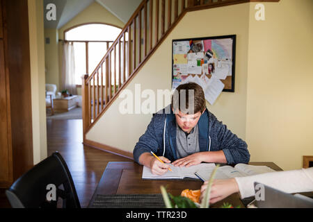 Young man studying on table at home Stock Photo
