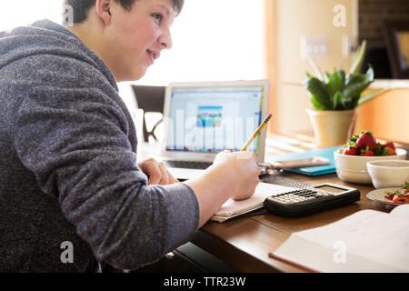 Young man studying on wooden table at home Stock Photo