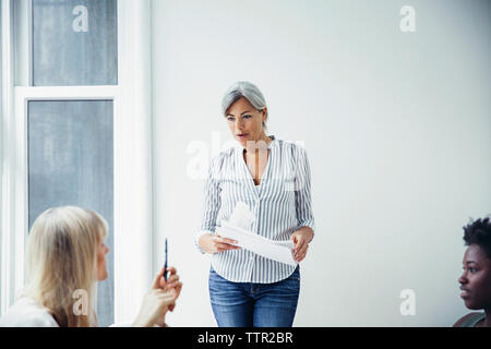 Mature businesswoman discussing with colleagues in creative office Stock Photo