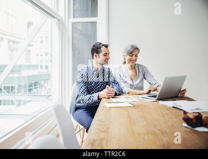 business colleagues using laptop in board room Stock Photo